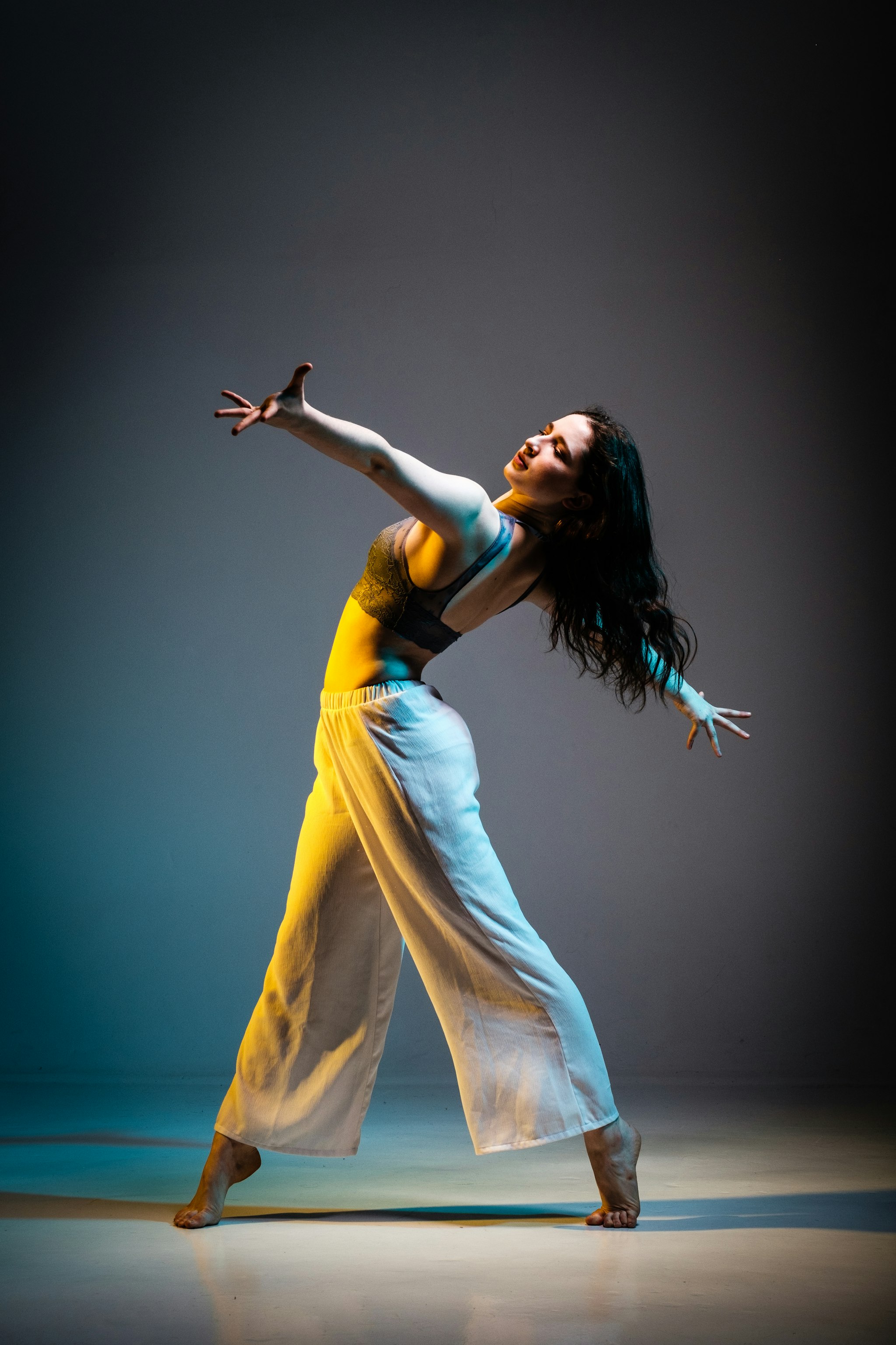 High-resolution cinematic shot of a ballet dancer on a dark stage, dramatic spotlight, delicate silk textures, dust motes in the air, graceful motion frozen in time.